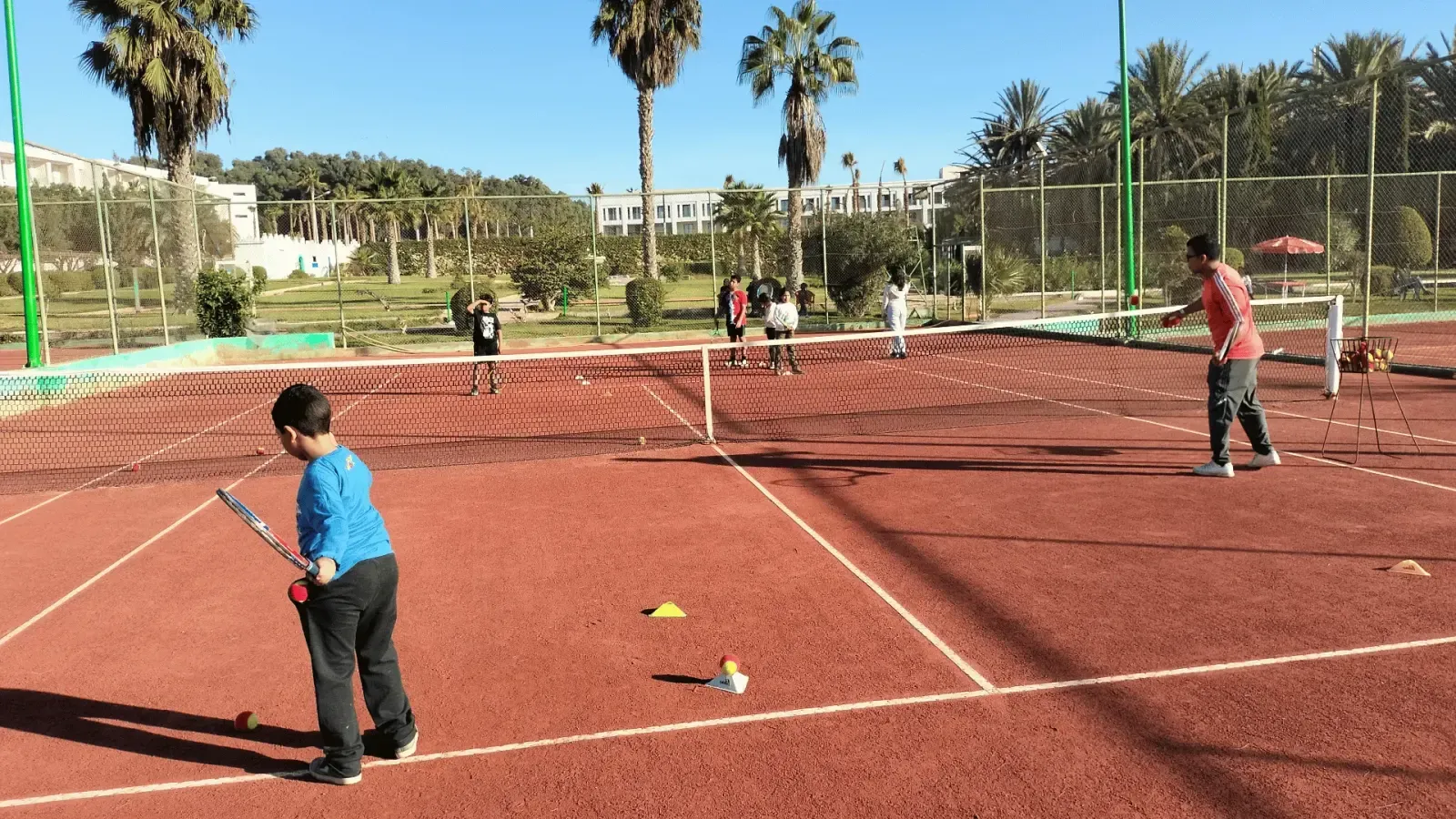 Séance de mini-tennis à l'école du club : un enfant à la balle mousse, cônes au sol