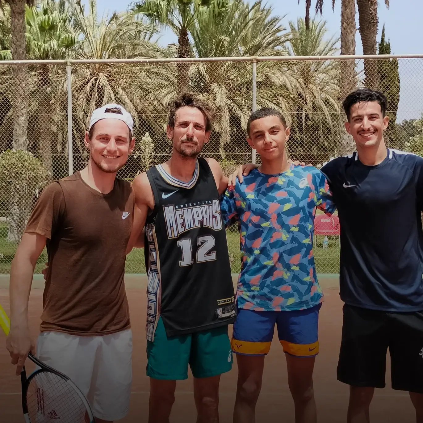 Stage di tennis per adulti: quattro partecipanti insieme sul campo in terra rossa a fine seduta