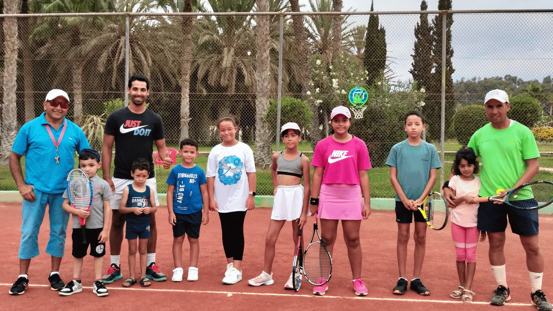 The community of the Agadir tennis school: young players and their coaches lined up on the clay